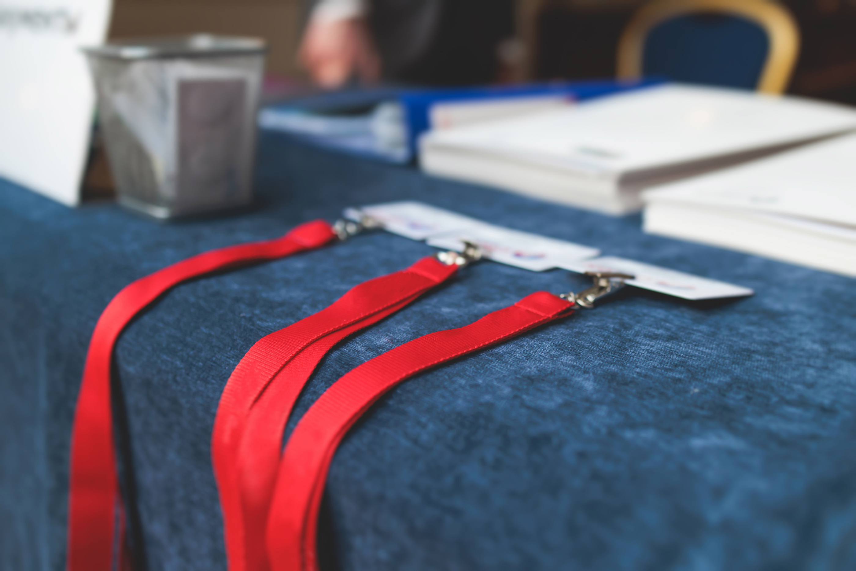 Registration desk table, process of checking in on a conference congress forum event, visitors and attendees receiving a name badge and entrance wristband bracelet and register electronic ticket